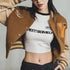 Person wearing a brown letterman jacket over a white crop top with text, on a plain background